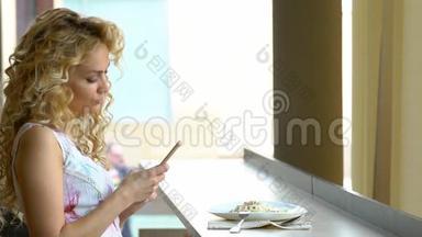 午餐休息时，一个年轻的金发女孩坐在咖啡馆里，用智能<strong>手机数码</strong>相机为自己画像