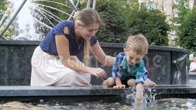 与妈妈一起在公园的喷泉中玩耍和泼水的可爱活泼的幼儿男孩慢动作视频