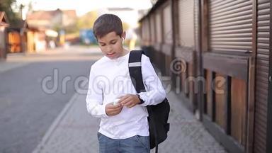 青少年男孩拿出无线耳机，然后放进耳朵里。 穿白色衬衫带背包的小男孩。 男孩