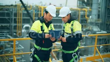 两名石油和天然气工人在炼油厂工作。