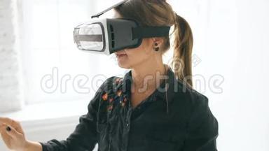 在室内的白色房间里，VR耳机里的女人抬起头，试图触摸虚拟现实中的物体