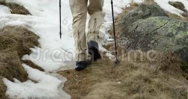 徒步旅行者背着背包走在雪地小径上。 后面跟着腿的细节。 真正的背包客成人徒步旅行或