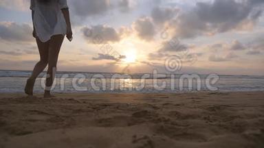 年轻快乐的女人穿着泳衣和衬衫在日落时去海边的水上。 享受暑假的女孩