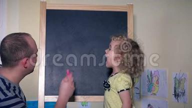 父亲带着他蹒跚学步的女儿，孩子在黑板上学习字母