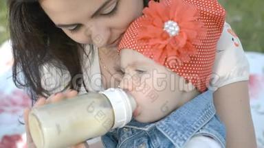 在公园里喂她刚出生的小女孩的奶瓶