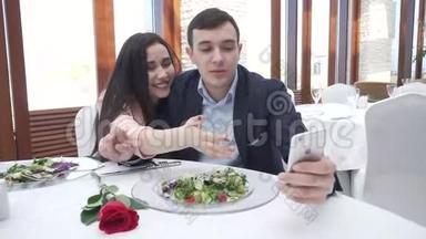 爱的幸福夫妻在餐厅通过iPhone慢动作的股票镜头在Instagram上自拍