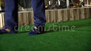 男人踩着绿色的门垫。 男人穿着袜子`绿色地毯上