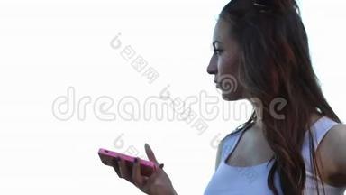 在一个炎热的夏天，穿着白色上衣的年轻女孩正在手机上输入一条信息。