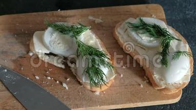 黑色背景的木板上有面包、黄油、鸡蛋和的特写三明治。 做三明治。