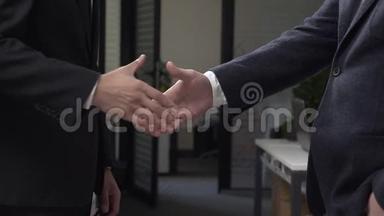 两个穿西装的成功商人在后台办公室握手，一个非洲商人，一个