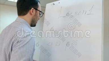 青年眼镜教师在挂图上写家庭作业练习