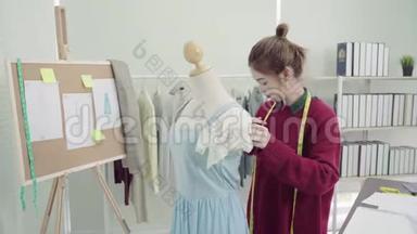 专业美丽的亚洲女时装设计师在工作室的人体模特服装设计上工作测量服装。