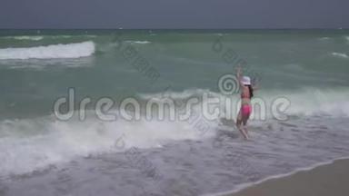 穿着泳衣的少女在迪拜海滩上快乐地跳进波斯湾的海浪中