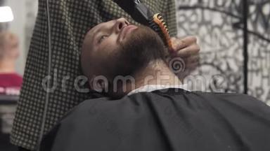 男式沙龙用电动剃须刀刮胡子。 有胡子的人