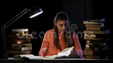 女孩坐在桌子旁看书。 黑色背景。 时间流逝