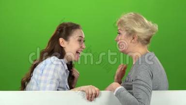 妈妈和女儿谈论各种话题。 绿色屏幕。 侧视图