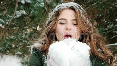 美丽的女孩吹着雪，雪<strong>花飞</strong>舞，一个可爱的年轻女子在雪地森林中的肖像，冬天的旅行