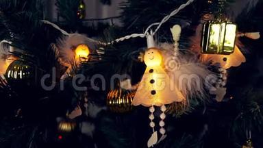 白色天使的电极挂在圣诞树上。 美丽可爱的白衣天使在黑暗中闪耀