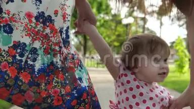 小宝宝学着爸爸妈妈走路，快乐的一家人在夏天公园散步