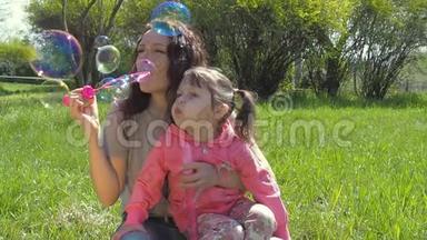 妈妈和女儿吹肥皂泡。 家庭在露天。 快乐的一家人在公园里玩泡泡。