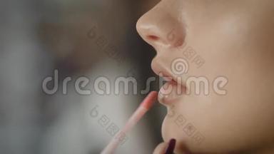 将润唇膏涂在模特`脸上。 这种工具可以保护嘴唇免受光线的照射，使<strong>皮肤干燥</strong>