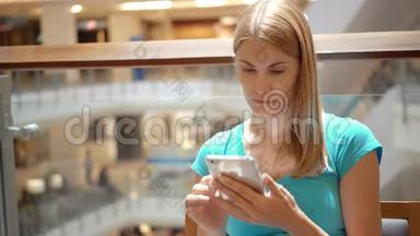 女人坐在购物<strong>中心广场</strong>上，使用智能手机，浏览看新闻，和朋友聊天