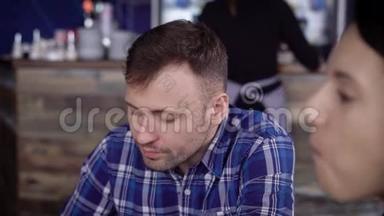 一个年轻人和他的朋友坐在餐馆里，喝着蓝色杯子里的咖啡。学生吃早餐