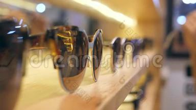 女顾客在商场货架上选购棕色镜片的太阳镜。4K.慢动作。