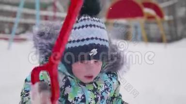 一个<strong>小孩</strong>在<strong>冬天</strong>的公园里玩雪.. 孩子拿着铲子，公园里有很多雪。 有趣的游戏