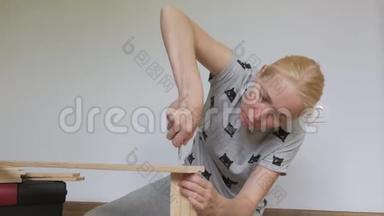 一个<strong>女人坐在地板上</strong>收集房间里<strong>的</strong>木制家具，用螺丝刀拧螺丝。