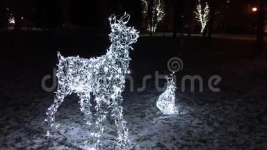 晚上，孩子们在一个冬天的公园里散步，靠近发光的动物身影。 兔子和鹿是由LED灯泡组成的花环。