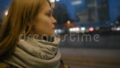 年轻的女士正穿着有轨电车向窗外眺望城市的夜生活