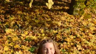 秋天公园里，小可爱的女孩把落叶的黄色的枫叶扔了出去