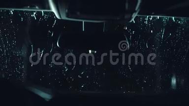 水滴沿着挡风玻璃流下。 一辆挡风玻璃汽车的内景。 深黑色电影画面.. 进程阶段