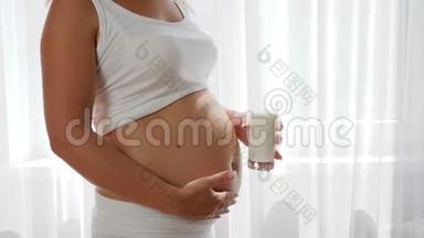 孕妇持有玻璃牛奶，并在肚子、奶制品背景上签字认可