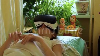 悲伤生病<strong>的</strong>白种人女孩<strong>躺在</strong>病<strong>床上</strong>，<strong>躺在</strong>一条毯子下，戴着VR眼镜。