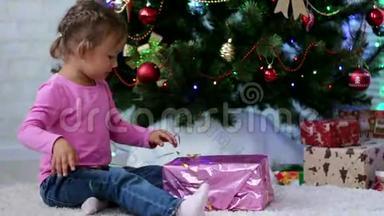 小女孩在圣诞树附近打开<strong>礼物盒</strong>。 儿童撕纸<strong>礼品</strong>