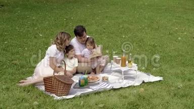 野餐时孩子们在草地上休息的幸福家庭。 家庭生活中的幸福与和谐..