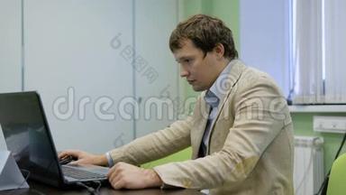 他办公室的经理在用笔记本电脑。 从笔记本电脑屏幕上读取信息。 热心的上班族。 一个男人