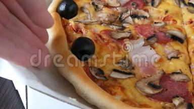 手拿一块意大利大比萨饼，里面有黑橄榄、培根、腊肠和奶酪