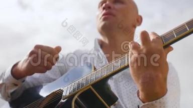 人在大自然中弹吉他，在田野里唱歌.. 吉他手触摸吉他弦。 中弹。