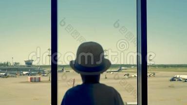 机场里的一个孩子。 一个男孩透过窗户看机场跑道。