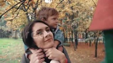 年轻的妈妈抱着可爱的小男孩，小男孩抱着她在令人惊奇的秋天公园4k附近的喂鸟者