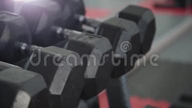 训练用的哑铃躺在健身房的架子上。