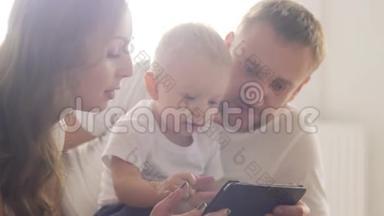父母教孩子使用移动小工具。 有孩子的年轻父母使用平板电脑。