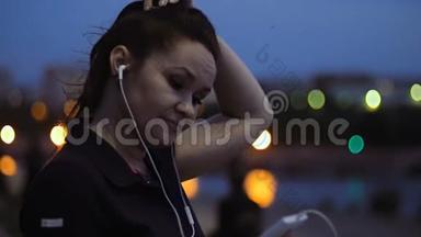 晚上，一个女人站在河堤上，用手指<strong>滚动</strong>她智能手机的<strong>屏幕</strong>。