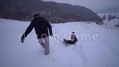 年轻的幸福家庭在雪林里玩得很开心。 父亲把他的小儿子卷在雪橇上。 晚上散步。 <strong>爸爸</strong>和<strong>爸爸</strong>