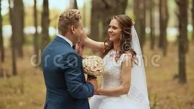 森林里快乐的新娘和新郎。 你的手。 新郎用花束拥抱新娘。 幸福的眼泪。