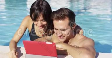 游泳池的微笑情侣使用数字设备