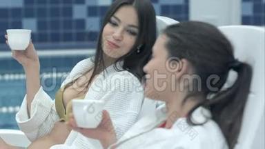 两个年轻快乐的女人正在喝茶，其中一个正在受到蚊子的攻击